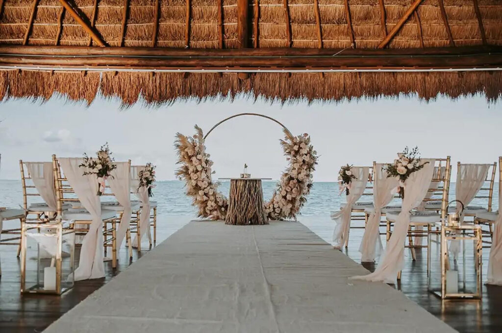 Planning a destination wedding with a stunning oceanfront ceremony setup under a thatched-roof gazebo in Mexico.