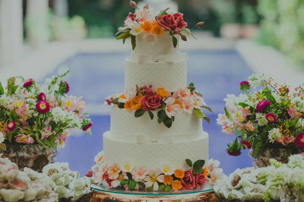 Elegant floral wedding cake surrounded by tropical flowers, perfect for couples planning a destination wedding.